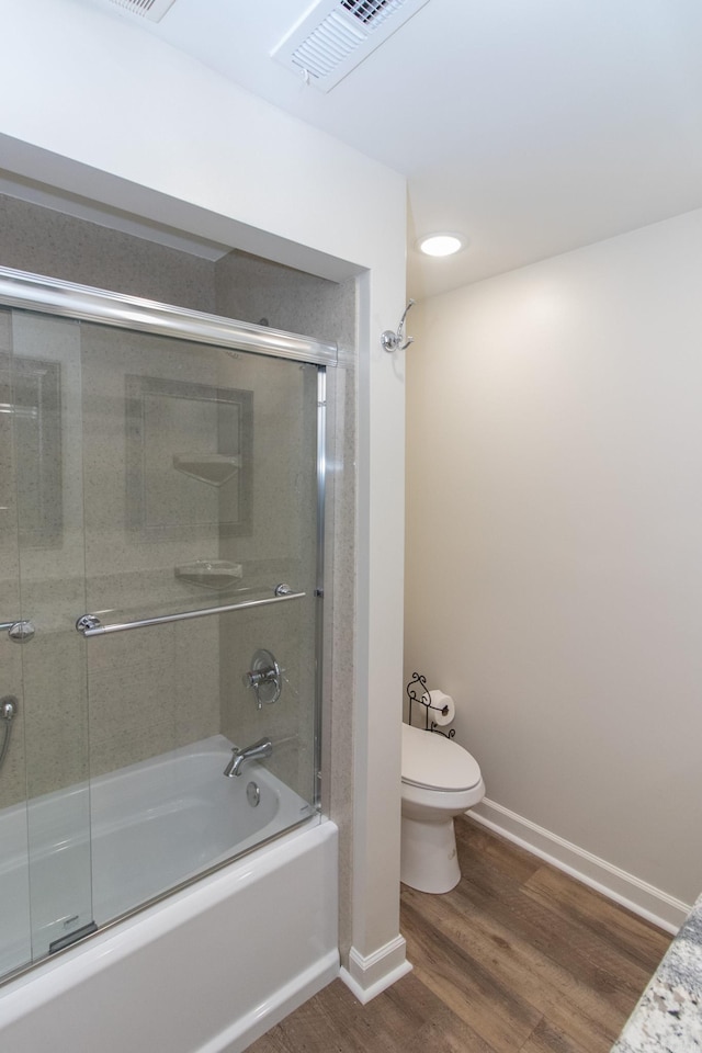 bathroom with toilet, hardwood / wood-style flooring, and combined bath / shower with glass door