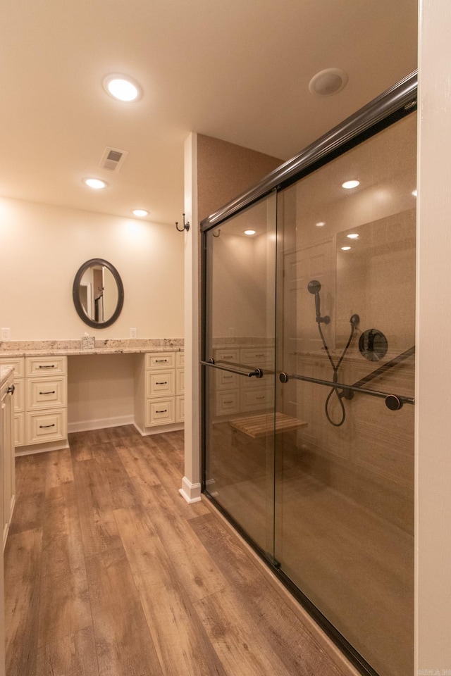 bathroom featuring walk in shower, vanity, and hardwood / wood-style floors