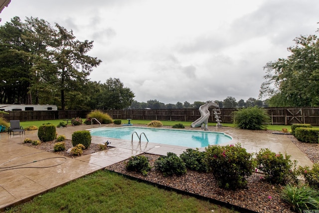 view of swimming pool with a water slide, a patio area, and a lawn