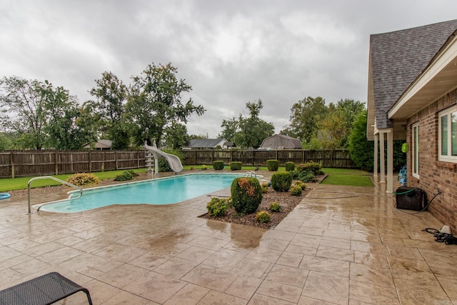 view of pool featuring a water slide and a patio