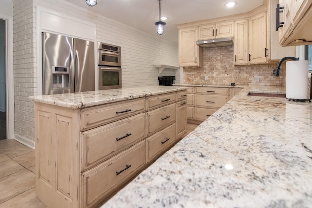 kitchen with ornamental molding, light tile patterned floors, light stone countertops, hanging light fixtures, and appliances with stainless steel finishes