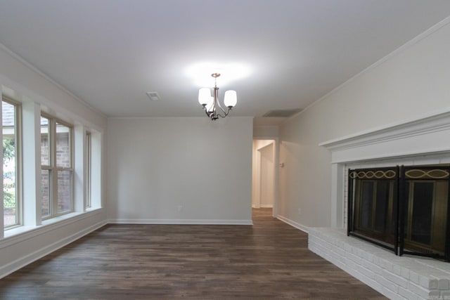 unfurnished living room featuring crown molding, dark wood-type flooring, a chandelier, and a brick fireplace