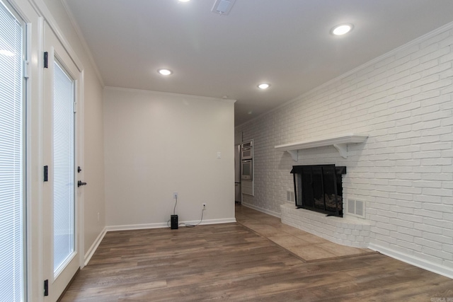 unfurnished living room featuring ornamental molding, hardwood / wood-style floors, a brick fireplace, and brick wall