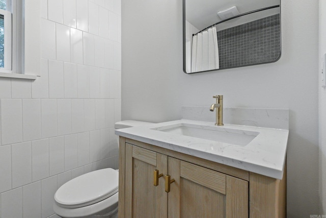 bathroom with vanity, toilet, a shower with shower curtain, and tile walls