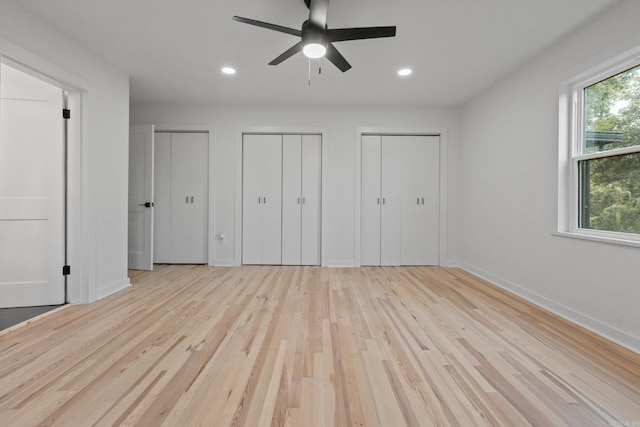 unfurnished bedroom featuring multiple closets, ceiling fan, and light hardwood / wood-style floors