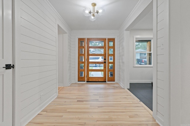 foyer featuring crown molding, light hardwood / wood-style flooring, and a notable chandelier