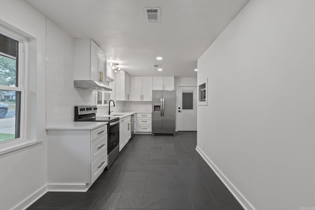 kitchen with backsplash, dark tile patterned floors, stainless steel appliances, white cabinetry, and sink