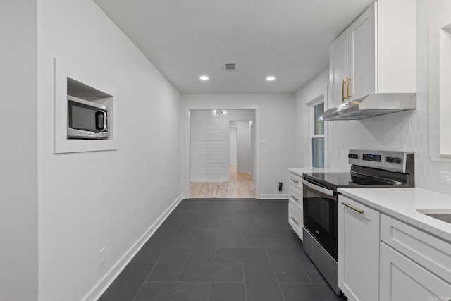 kitchen with dark tile patterned flooring, white cabinets, appliances with stainless steel finishes, and tasteful backsplash