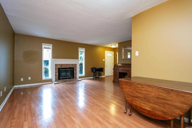 unfurnished living room featuring a fireplace, a textured ceiling, and light hardwood / wood-style flooring