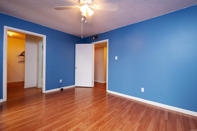 empty room featuring a textured ceiling, ceiling fan, and light hardwood / wood-style floors