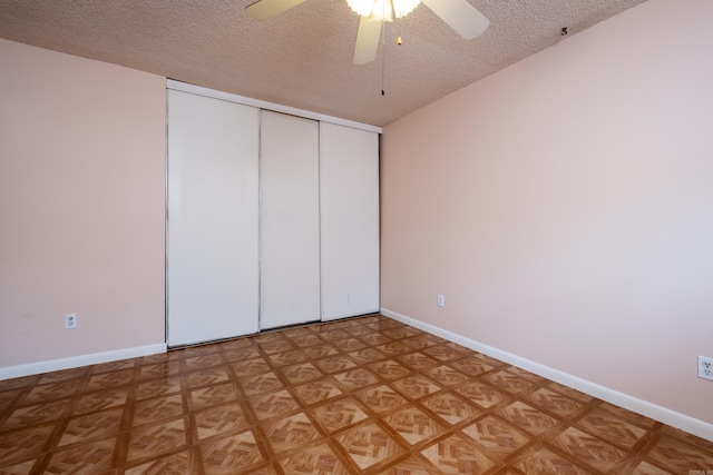 unfurnished bedroom with a textured ceiling, ceiling fan, a closet, and parquet flooring