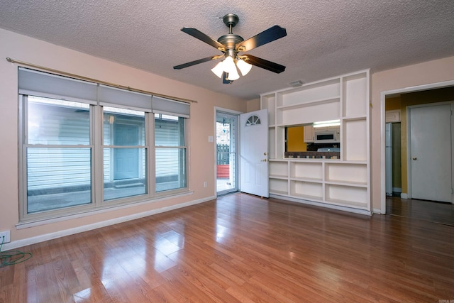 unfurnished living room featuring a textured ceiling, ceiling fan, hardwood / wood-style floors, and built in shelves