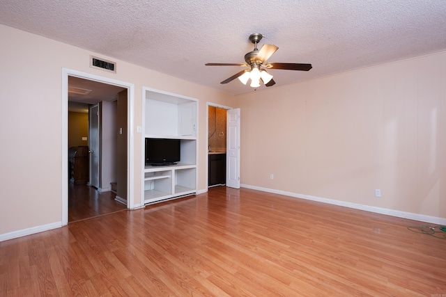 unfurnished living room featuring light wood-type flooring, ceiling fan, and a textured ceiling