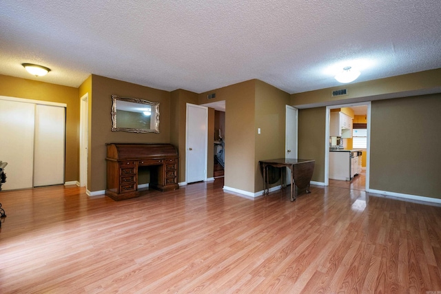 unfurnished living room featuring light wood-type flooring and a textured ceiling