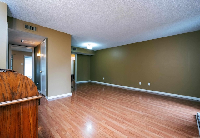 empty room featuring a textured ceiling and light hardwood / wood-style floors