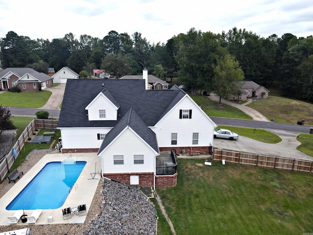 rear view of property featuring a yard, a fenced in pool, and a patio