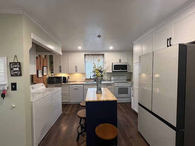 kitchen with white cabinets, stainless steel appliances, butcher block countertops, a kitchen island, and washing machine and dryer