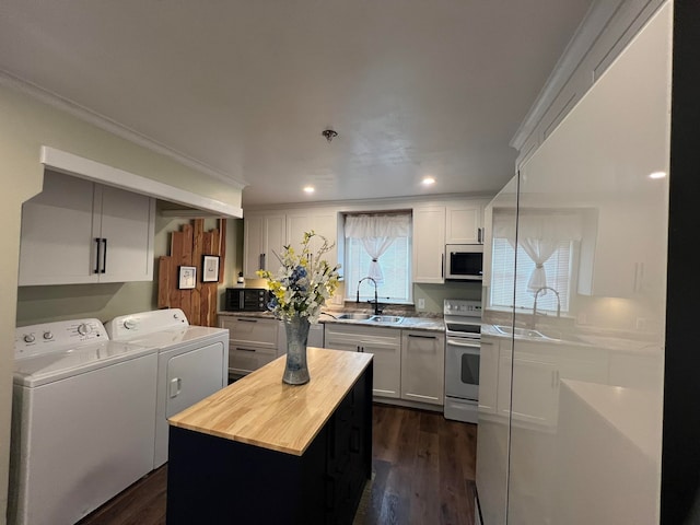 kitchen with a wealth of natural light, white range with electric stovetop, a center island, and washing machine and dryer