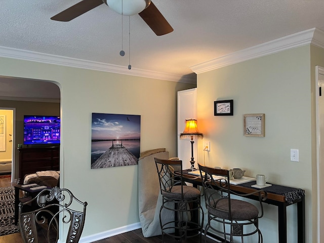 dining room featuring ornamental molding, dark wood-type flooring, a textured ceiling, and ceiling fan