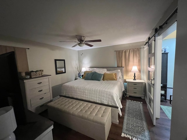 bedroom with a barn door, ceiling fan, and dark wood-type flooring