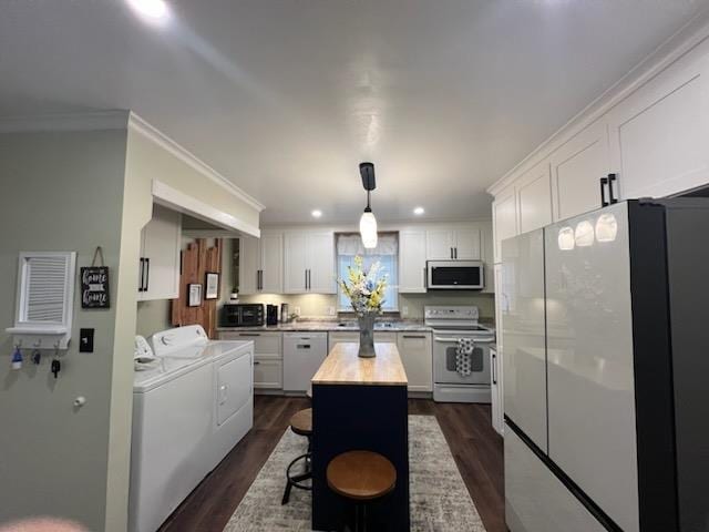 kitchen featuring white appliances, a kitchen island, white cabinetry, and washer and clothes dryer