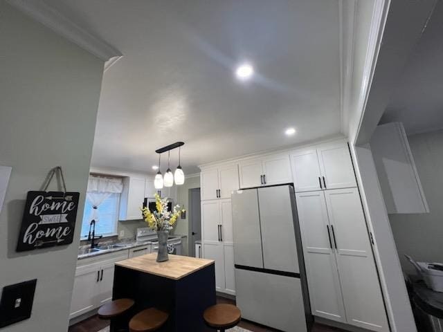 kitchen featuring stainless steel appliances, a kitchen island, sink, hanging light fixtures, and white cabinets