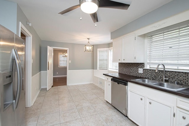 kitchen with white cabinets, backsplash, ceiling fan with notable chandelier, appliances with stainless steel finishes, and sink