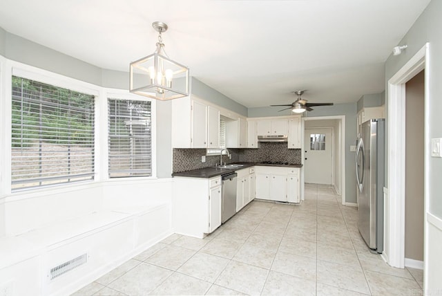 kitchen featuring ceiling fan with notable chandelier, stainless steel appliances, white cabinetry, sink, and pendant lighting