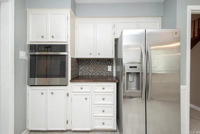 kitchen with stainless steel appliances, decorative backsplash, and white cabinetry