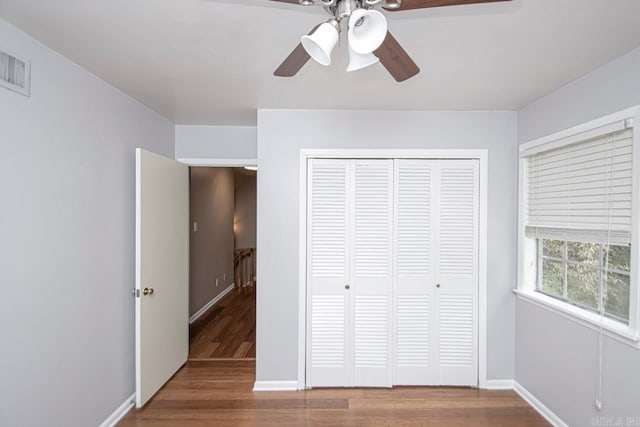 unfurnished bedroom with ceiling fan, a closet, and hardwood / wood-style flooring