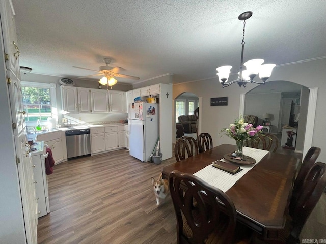 dining space with ceiling fan with notable chandelier, crown molding, wood-type flooring, and a textured ceiling