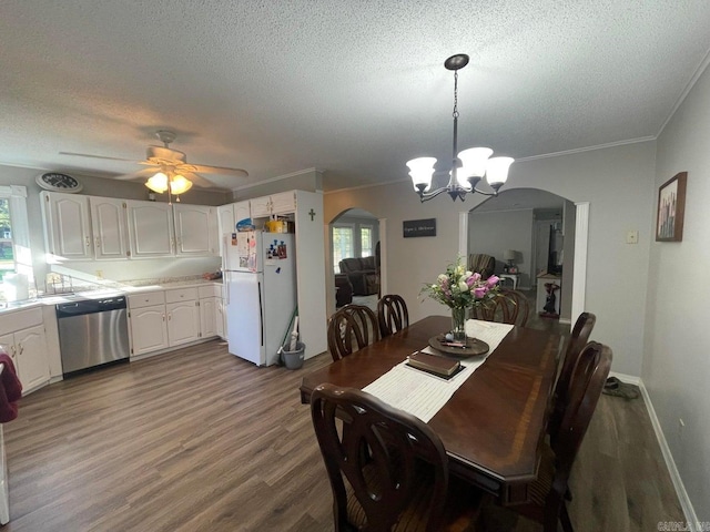 dining room featuring a textured ceiling, ornamental molding, ceiling fan with notable chandelier, and wood-type flooring