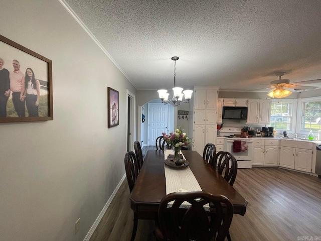 dining room with a textured ceiling, ornamental molding, ceiling fan with notable chandelier, and hardwood / wood-style flooring