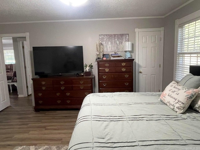 bedroom with ornamental molding, multiple windows, a textured ceiling, and wood-type flooring