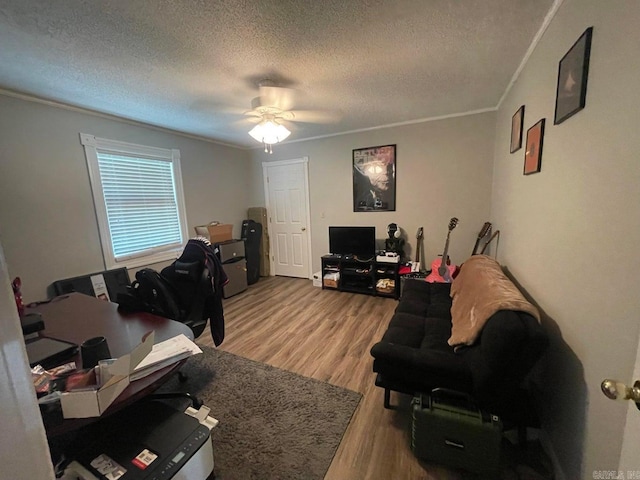 living room featuring a textured ceiling, ceiling fan, ornamental molding, and light wood-type flooring