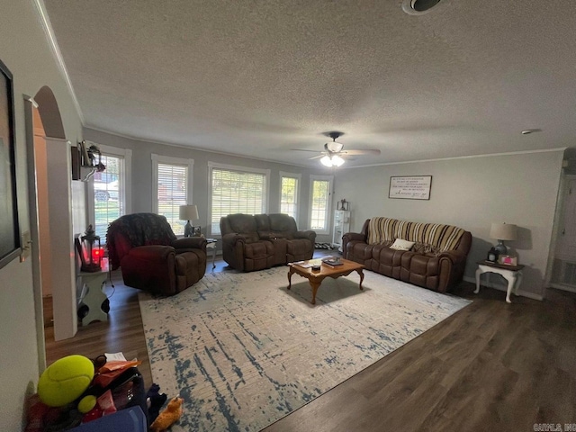 living room with a textured ceiling, dark wood-type flooring, ceiling fan, and crown molding