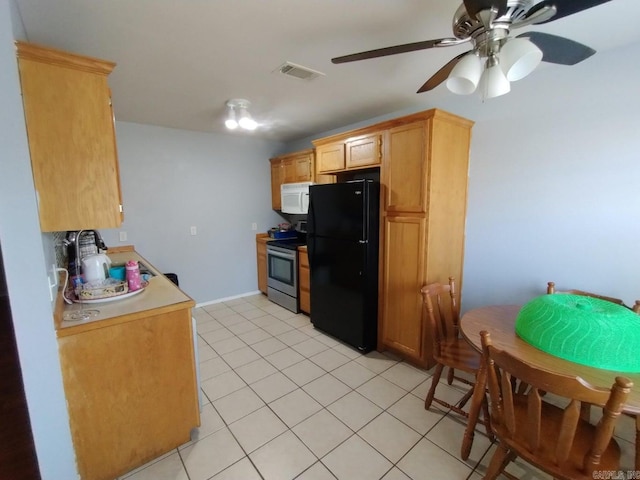 kitchen with stainless steel electric range oven, ceiling fan, black refrigerator, and light tile patterned flooring