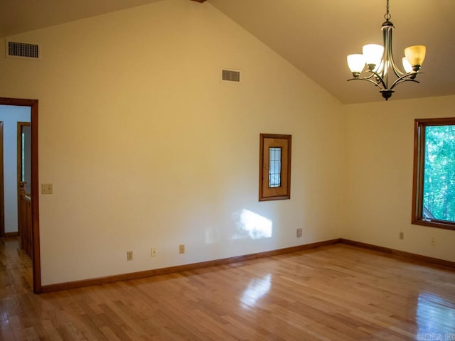 spare room with an inviting chandelier, high vaulted ceiling, and light hardwood / wood-style floors