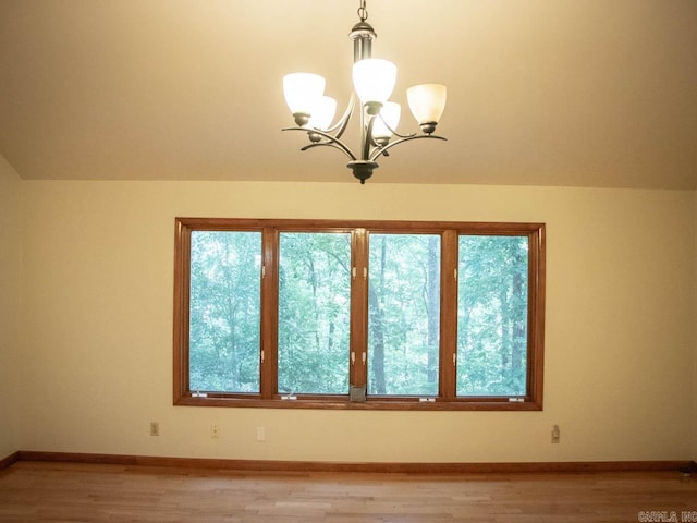 empty room featuring light wood-type flooring, a notable chandelier, and a healthy amount of sunlight