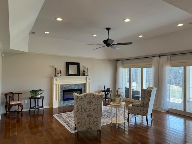 living room featuring ceiling fan, dark hardwood / wood-style flooring, and a premium fireplace