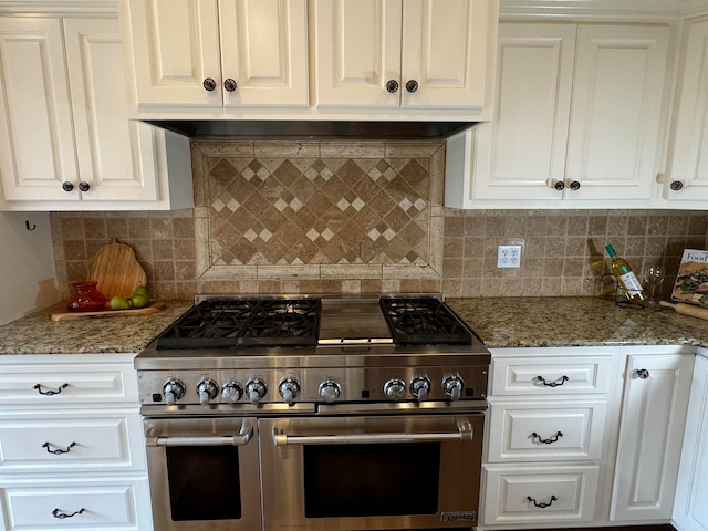 kitchen with stone countertops, range with two ovens, white cabinets, and decorative backsplash