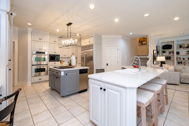 kitchen with hanging light fixtures, white cabinetry, sink, gray cabinets, and an island with sink