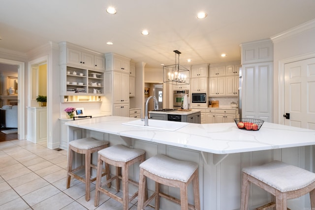 kitchen featuring oven, decorative light fixtures, a large island with sink, sink, and light tile patterned flooring