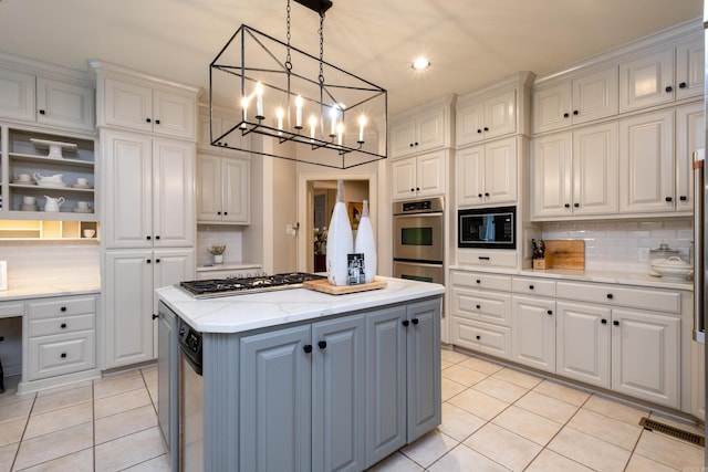 kitchen featuring light tile patterned floors, a kitchen island, decorative light fixtures, and appliances with stainless steel finishes