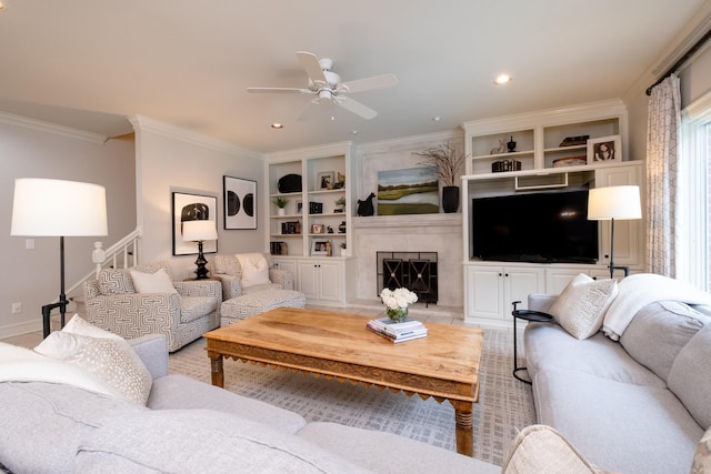 living room featuring a fireplace, ornamental molding, built in shelves, and ceiling fan