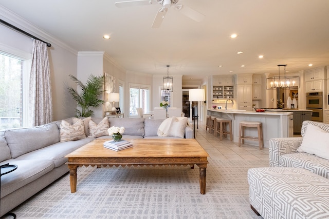 tiled living room with ceiling fan with notable chandelier, crown molding, and sink