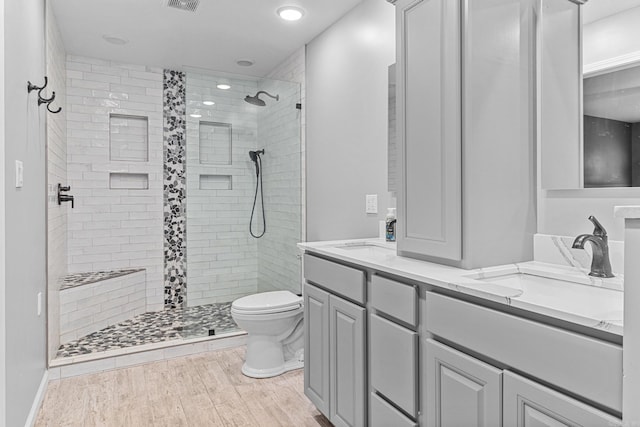 bathroom with tiled shower, vanity, toilet, and hardwood / wood-style floors