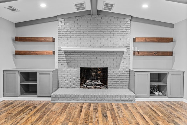 unfurnished living room featuring lofted ceiling, a brick fireplace, and hardwood / wood-style flooring