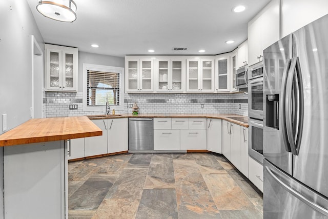 kitchen featuring backsplash, stainless steel appliances, sink, wooden counters, and white cabinets