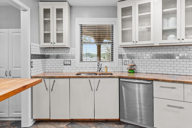 kitchen featuring white cabinets, backsplash, dishwasher, light stone counters, and sink